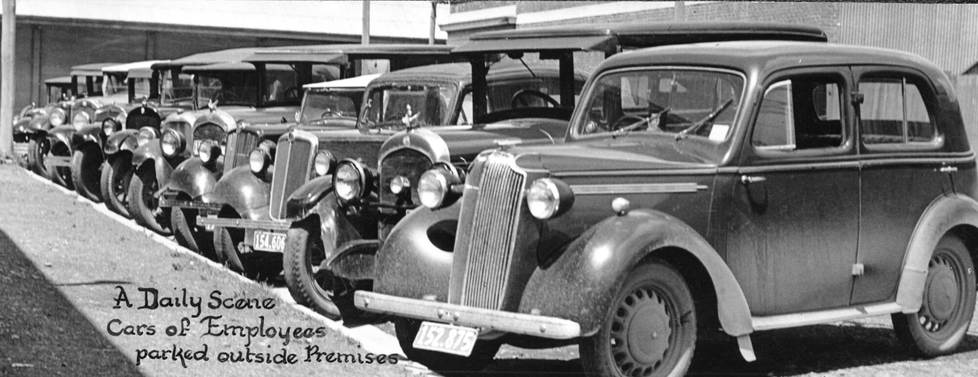 "A Daily Scene, Cars of Employees Parked Outside Premises"